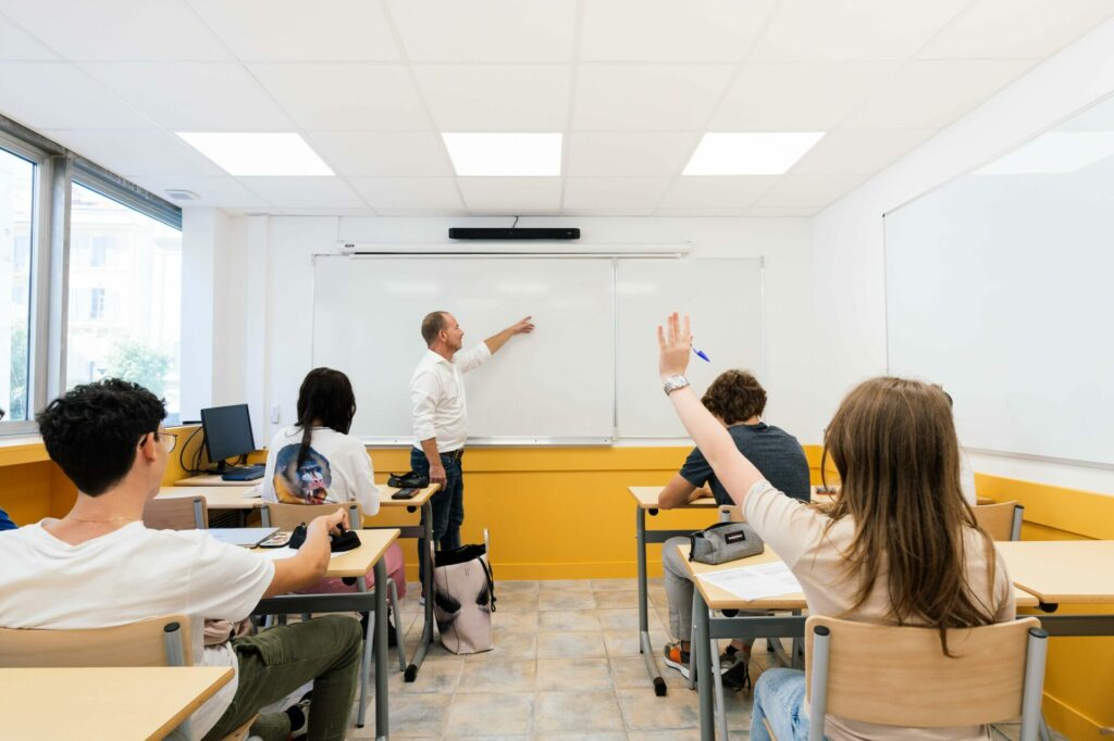 Classe d’élèves à l’école Michelet à Nice avec une élève qui lève la main pour se faire interroger par son professeur